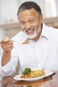 Older man smiling and eating a healthy plate of food. 